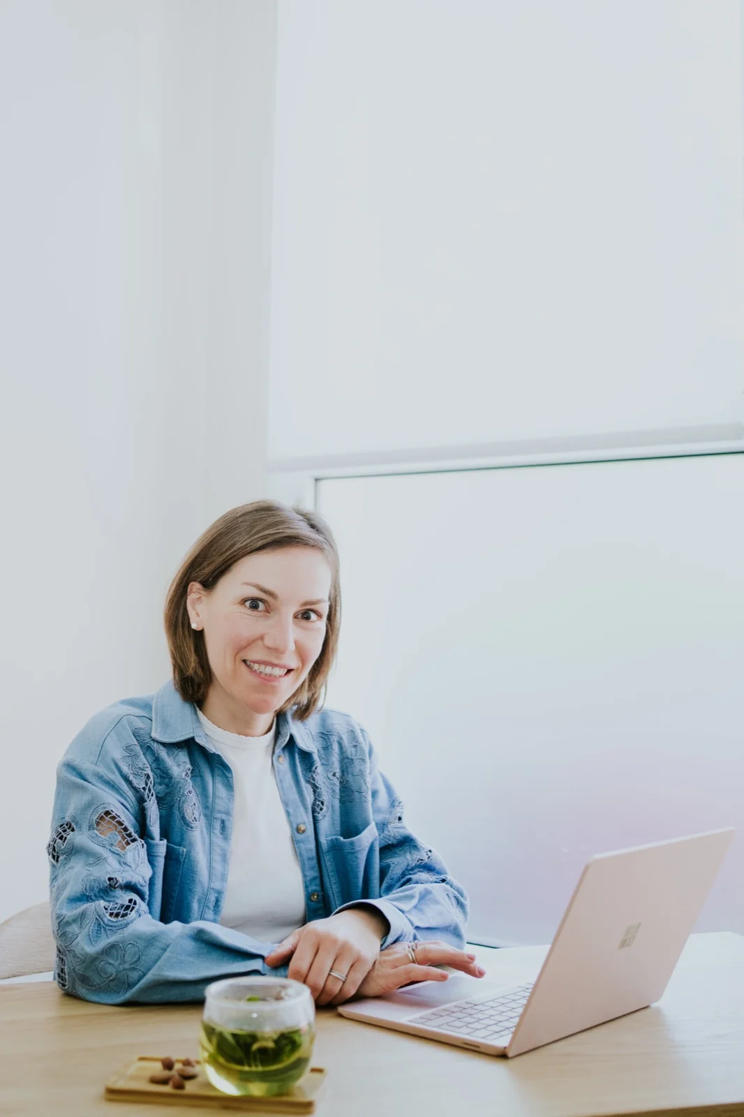 Aude à son bureau, souriante, devant son ordinateur et une tasse d'infusion
